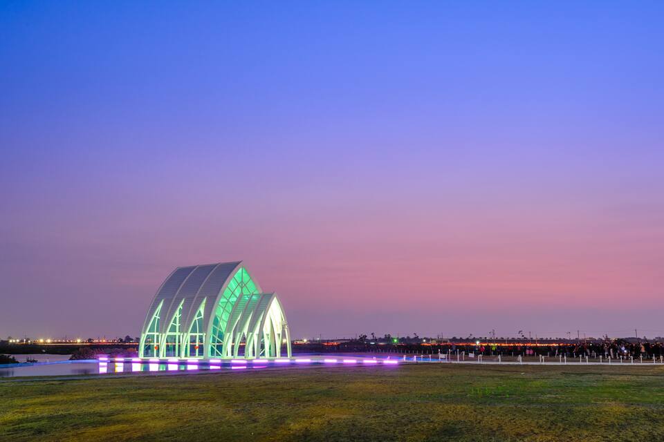 Um edifício moderno e iluminado, com uma estrutura de telhado curva e singular.