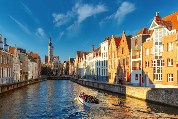 Tourist boat on canal Spiegelrei and Jan Van Eyck Square in the morning in Bruges, Belgium