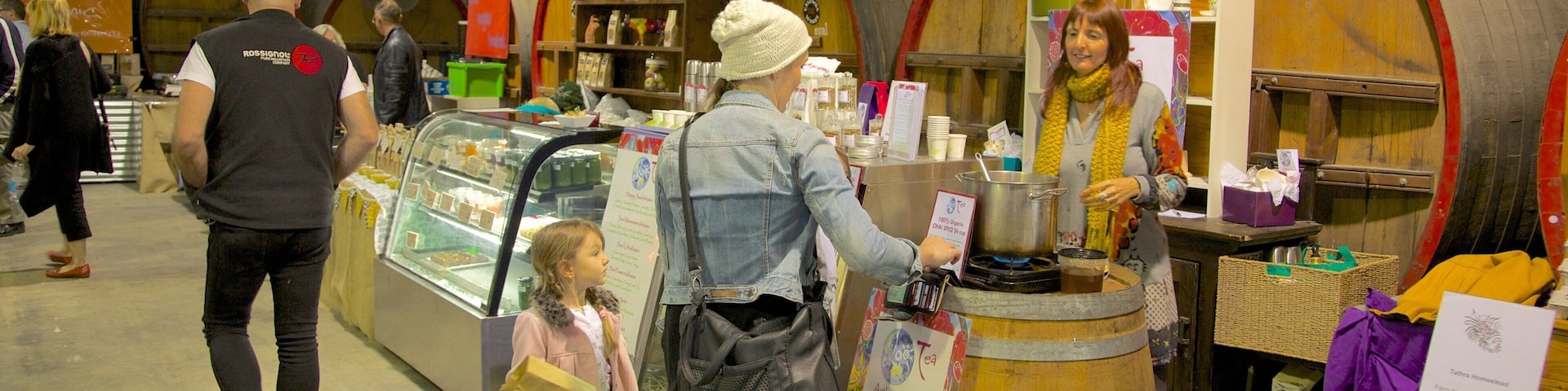 Un puesto de mercado con barriles de madera, una exhibición de huevos y una persona sirviendo té.