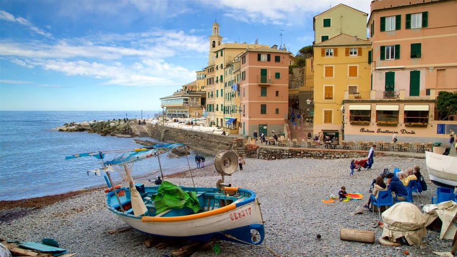 A pebble beach with boats, buildings, and a clear sky.
