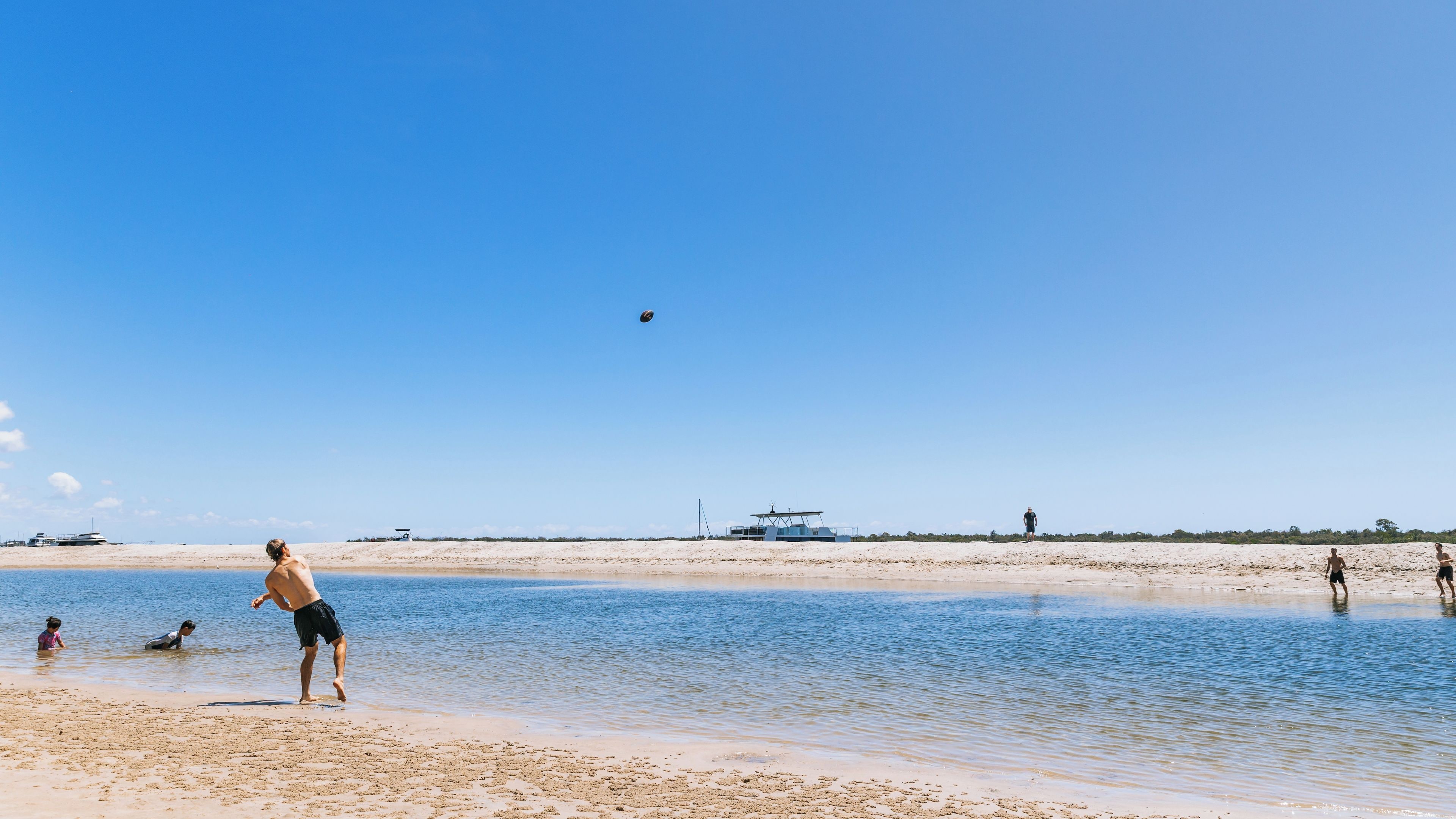 A beach with clear skies, calm water, and a few people.