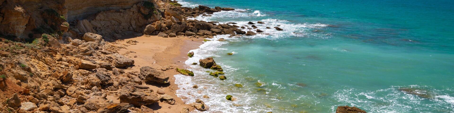 Cala del Faro which includes a beach, rocky coastline and general coastal views