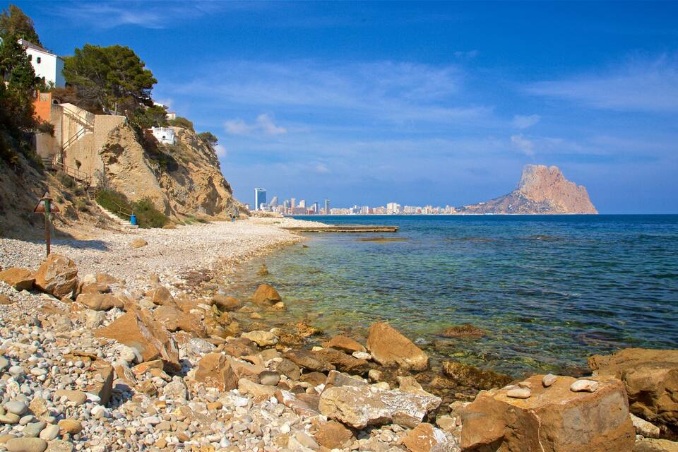 A rocky beach with a city skyline in the background.