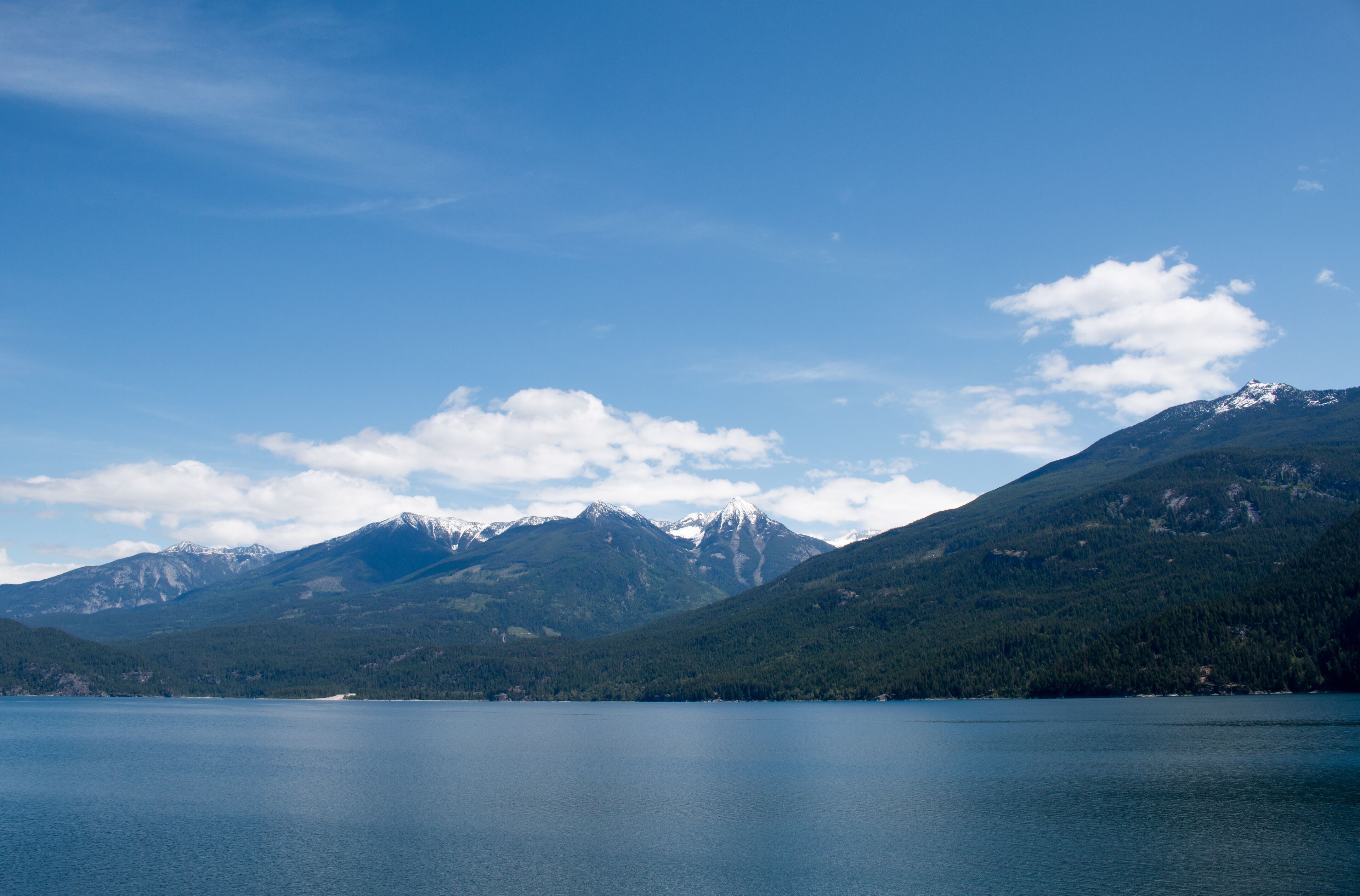 A lake surrounded by mountains with snow-capped peaks and dense forests.