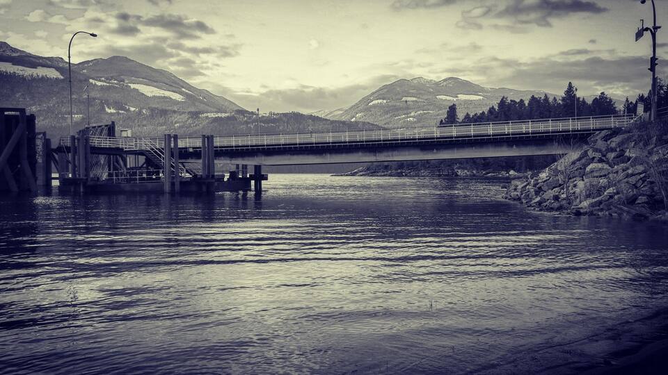A bridge over a river with mountains in the background.