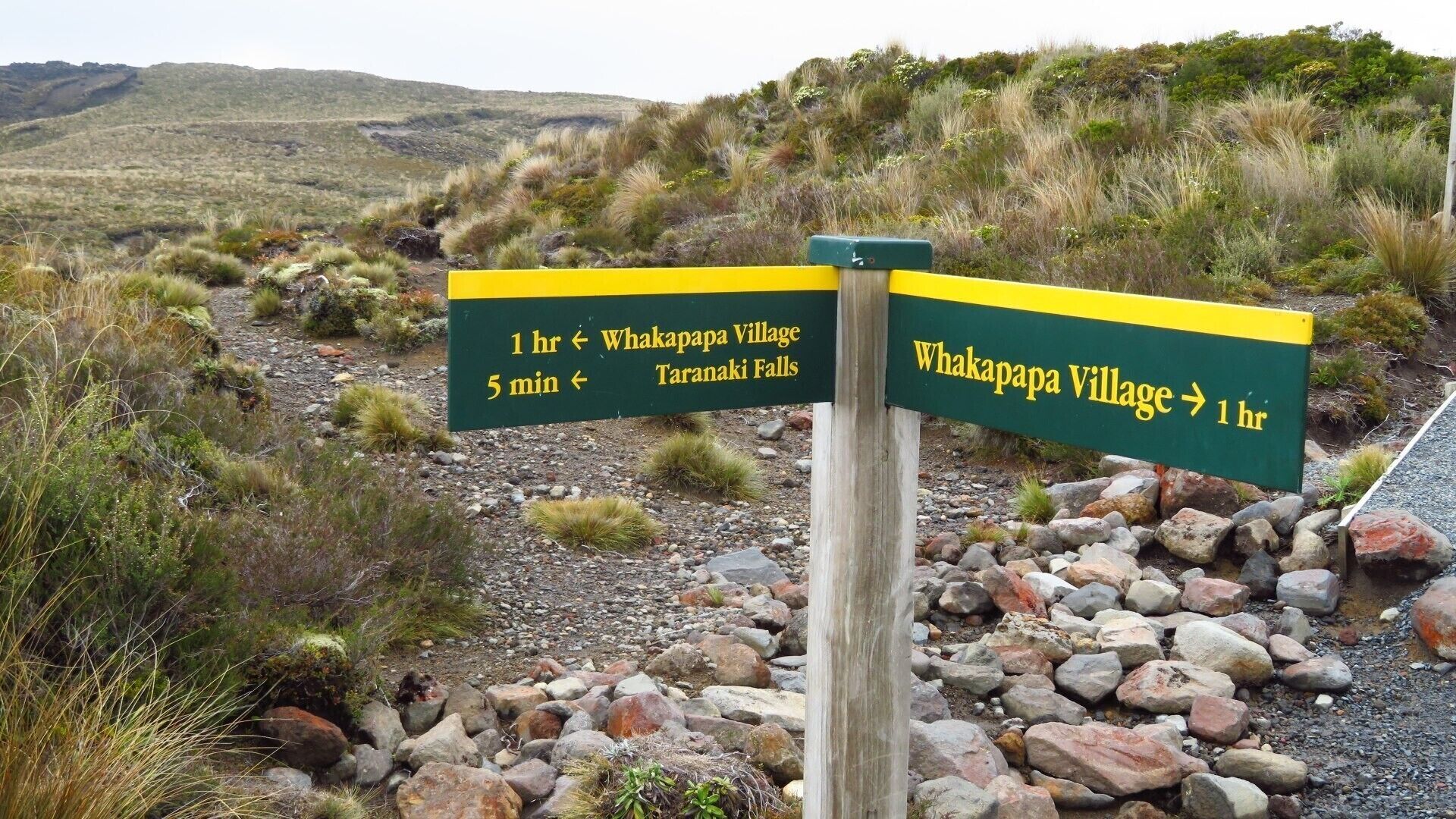 A directional signpost with destinations to Whakapapa Village and Taranaki Falls, indicating travel times.