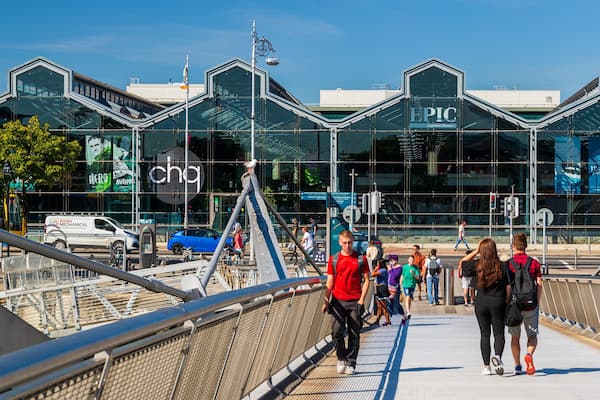 A pedestrian bridge with a glass building in the background labeled "PIC" and "JEANIE JOHNSTON".
