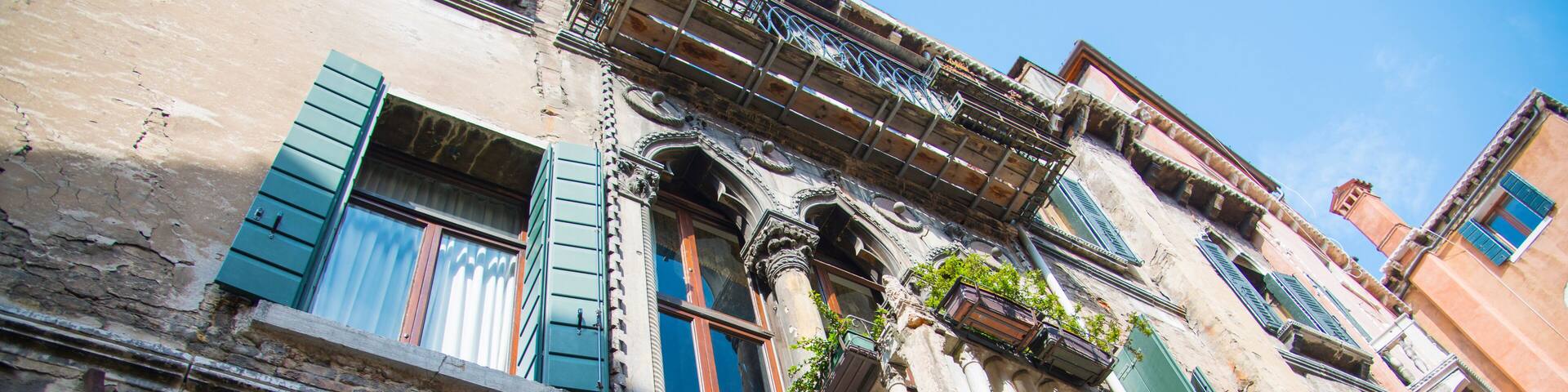 Un edificio antiguo de ladrillo con contraventanas verdes y balcones ornamentados.