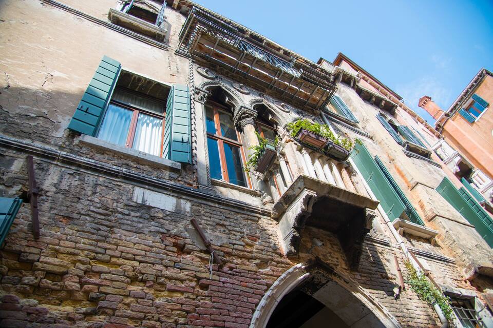 An old brick building with green shutters and ornate balconies.