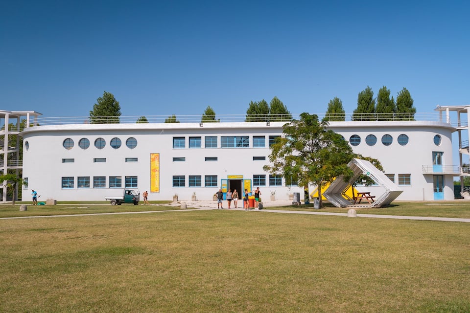 Een modern gebouw met een unieke spiraaltrap en een speelplaats ervoor.