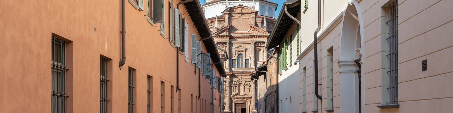 Cherasco, Cuneo, Italy - October 27, 2021: via dell'Ospedale with retirement home Ospedale degli Infermi, in the background Sanctuary of Our Lady of the People (1702), baroque style church