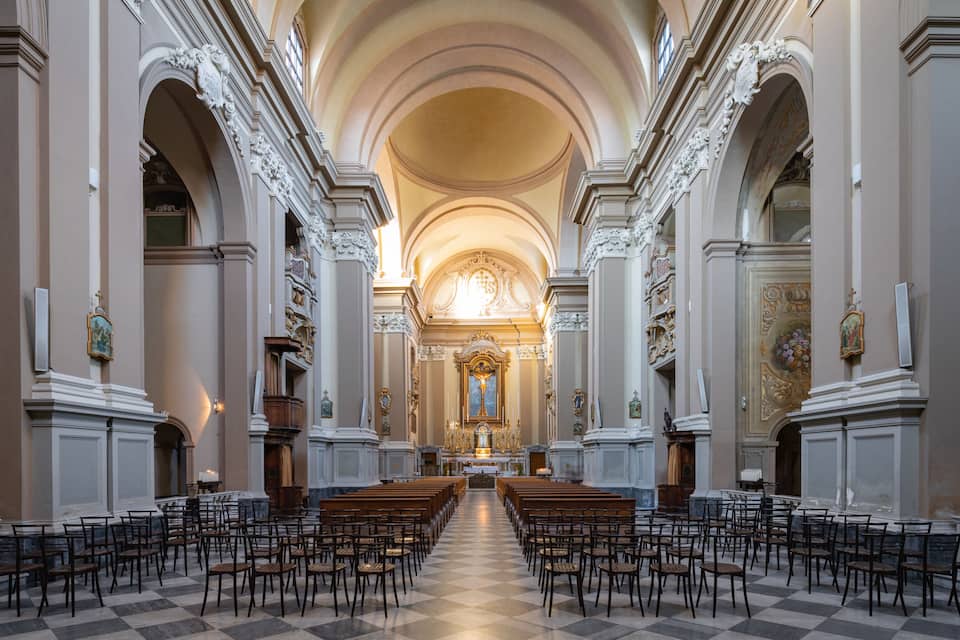 An ornate church interior with high ceilings, arched doorways, and a central altar.