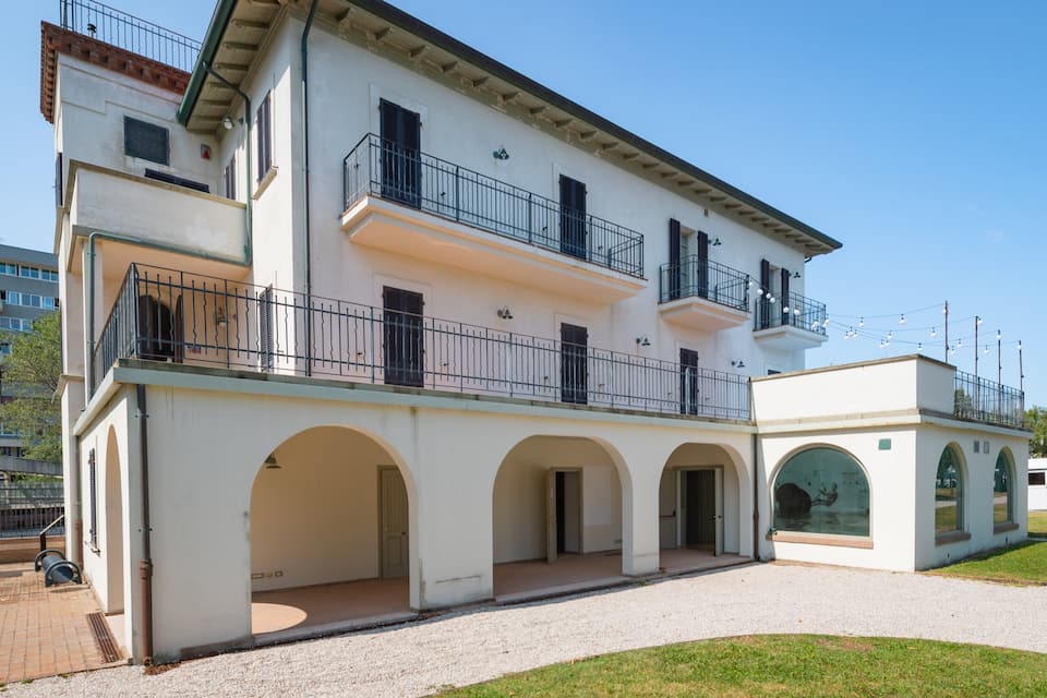 A two-story building with a white facade, black railings, and arched doorways.