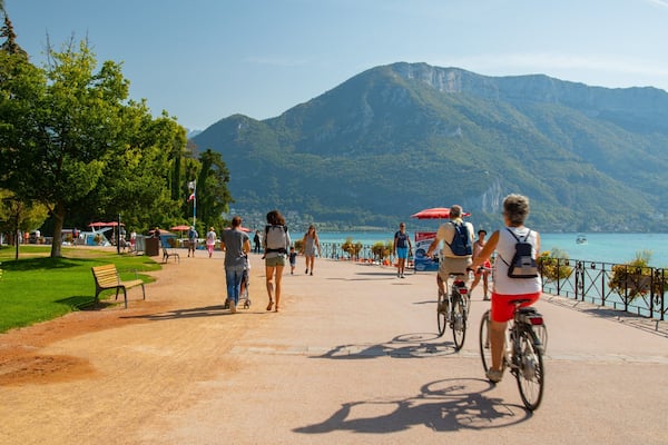 Un magnifique sentier au bord du lac, fréquenté par des cyclistes et des piétons, et bordé d’une végétation luxuriante et de montagnes.