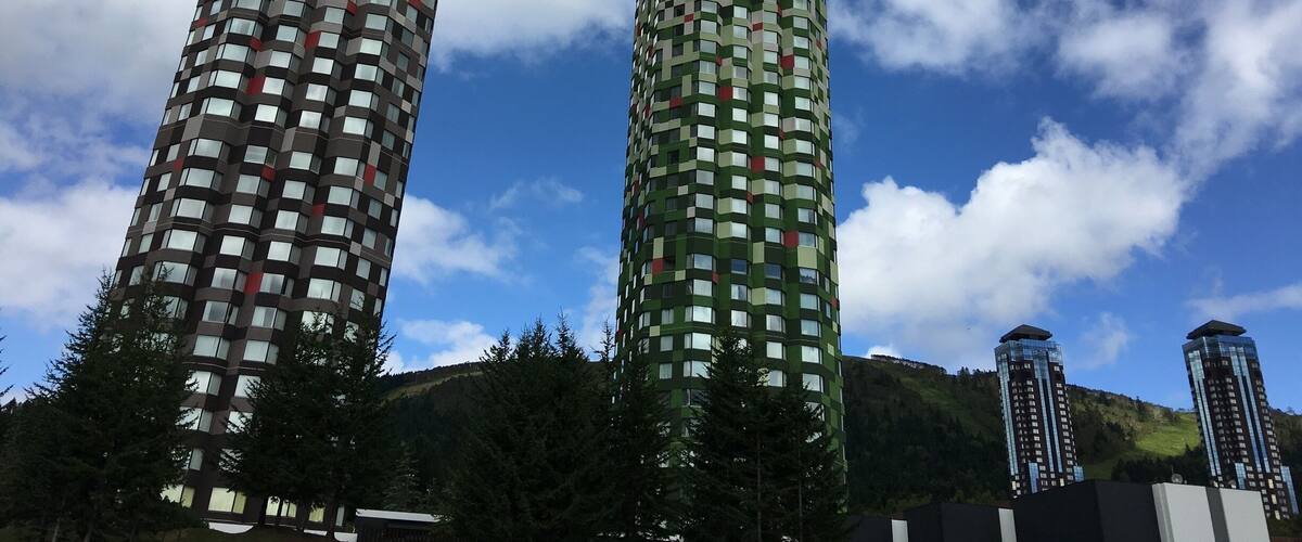 Two tall buildings with a mountainous background.