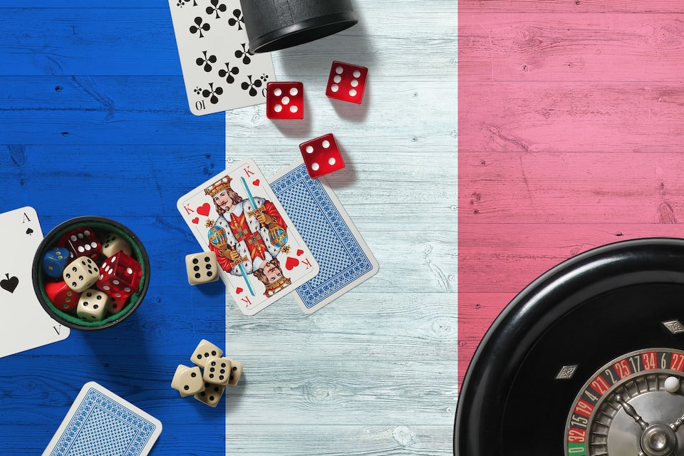 Ein blauer und pinkfarbener Holztisch mit Spielkarten, Würfeln und einem Roulette-Rad.