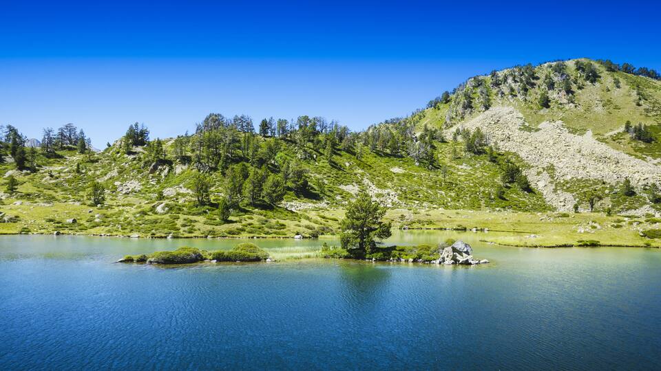 A serene lake surrounded by green hills and trees.