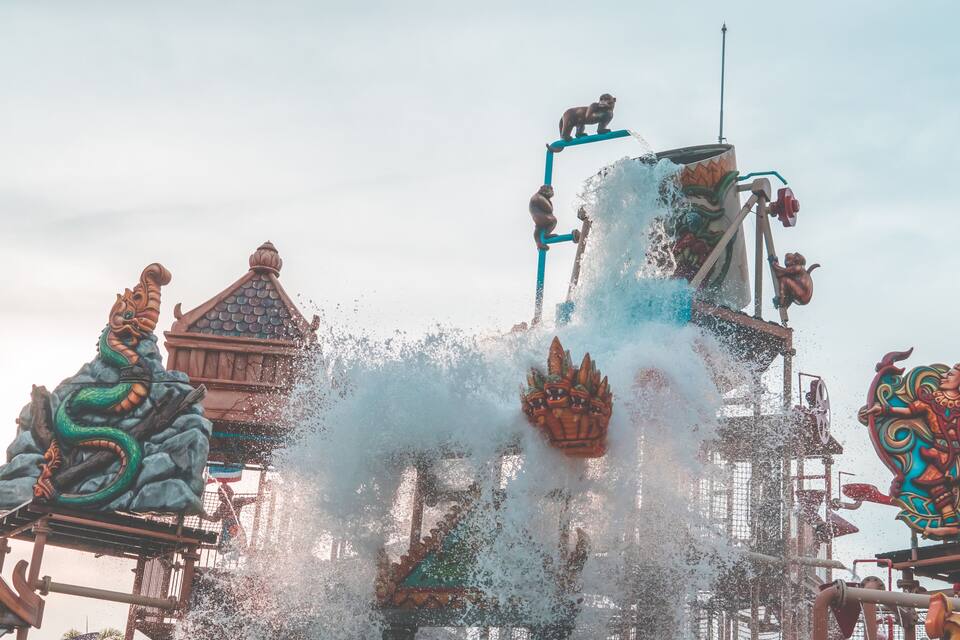 A water fountain with dragon sculptures and a traditional building in the background.