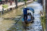 A man drive a gondola boat with tourist in a water canal at the Khlong Lat Mayom Floating Market, Thailand.