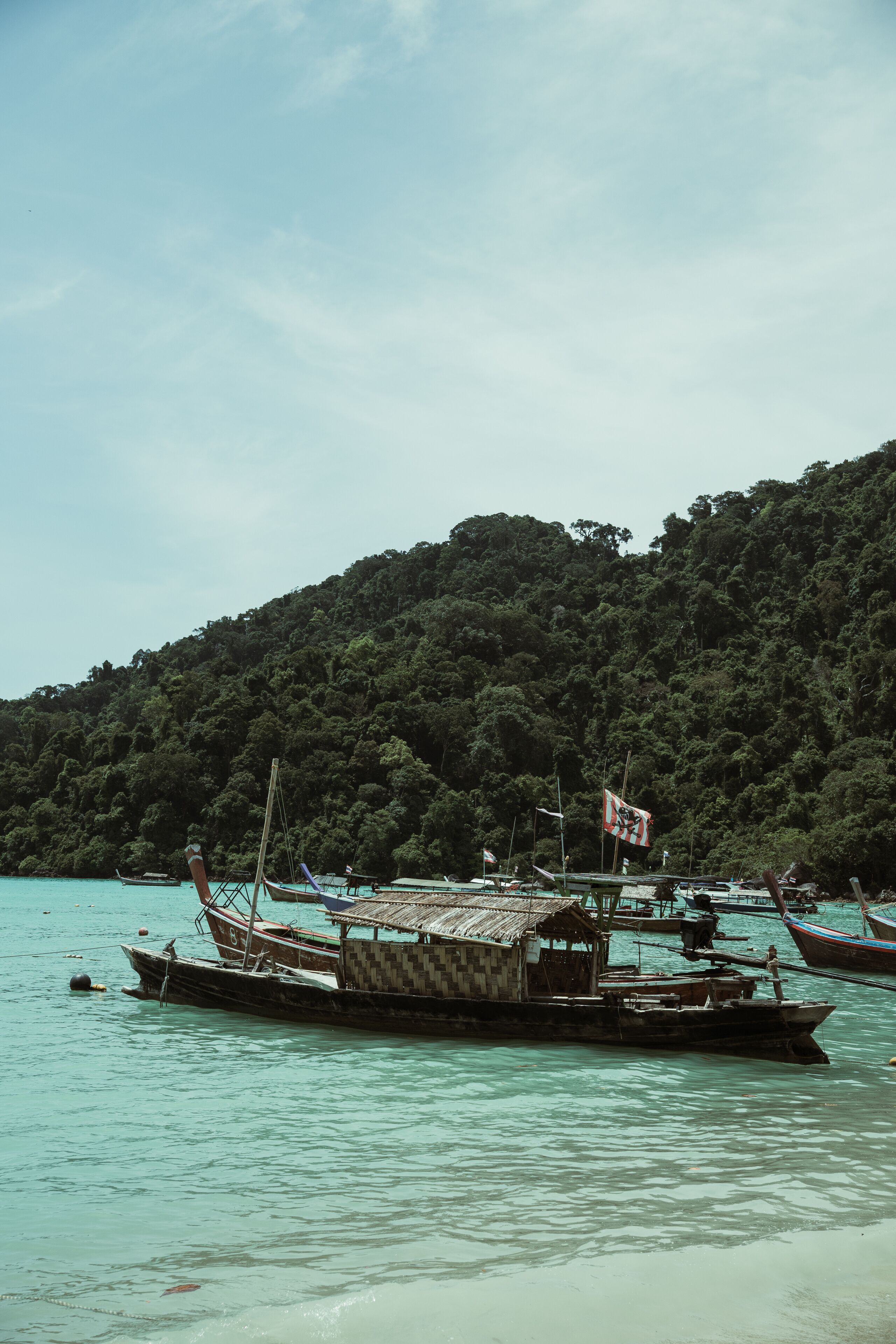 Traditional thai longtail boats floating on the calm turquoise water near Surin tropical island in Thailand
