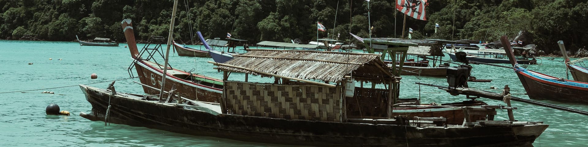 Traditional thai longtail boats floating on the calm turquoise water near Surin tropical island in Thailand