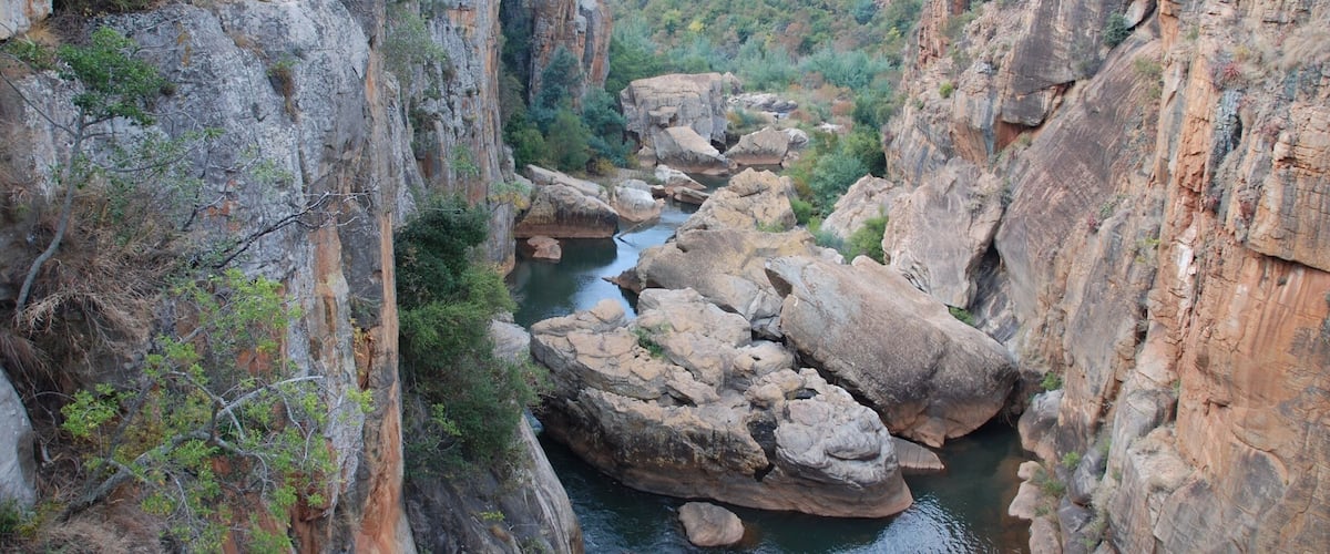 A canyon with a river flowing through it, surrounded by rocky cliffs and sparse vegetation.
