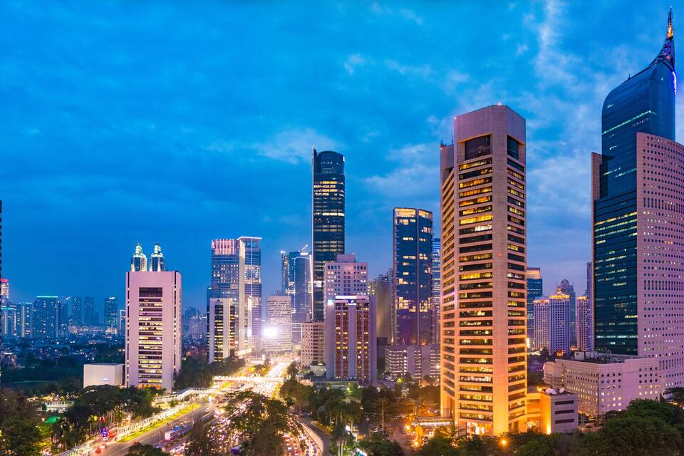 A cityscape with tall buildings and a busy highway at dusk.