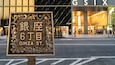 Une enseigne avec des caractères japonais et l’inscription « GINZA ST. » en anglais, devant un immeuble dont la façade porte l’inscription « GSX ».