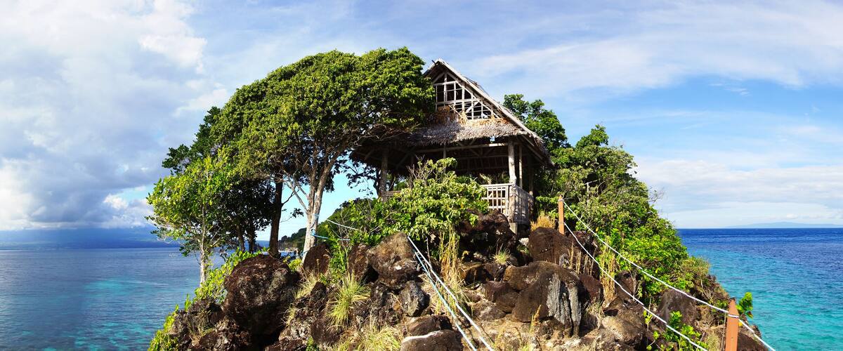 A wooden house on a rocky island surrounded by ocean.