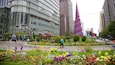 A cityscape with modern buildings, a distinctive spiral tower, and a vibrant flower garden.