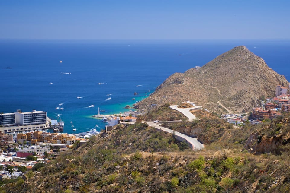 A coastal town with a prominent mountain, a winding road, and a marina with boats.