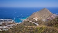 A coastal town with a prominent mountain, a winding road, and a marina with boats.