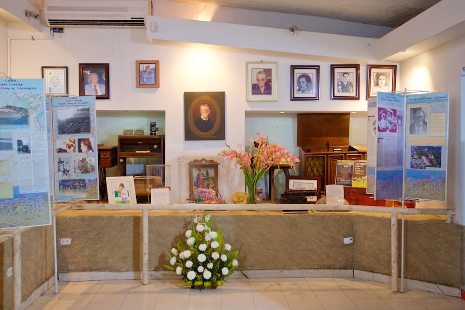 A reception area with framed photographs on the wall, a portrait, and informational displays.