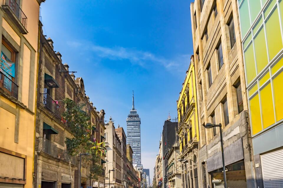 Rua com edifícios históricos e um arranha-céu moderno ao longe.