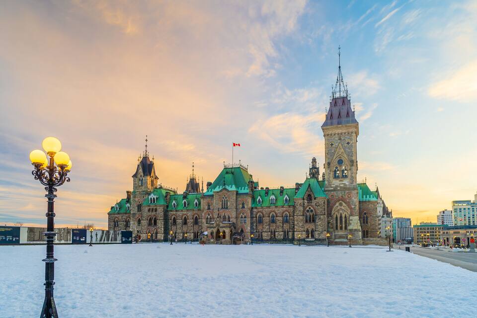 A historic building with a green roof and a tall tower, surrounded by snow.