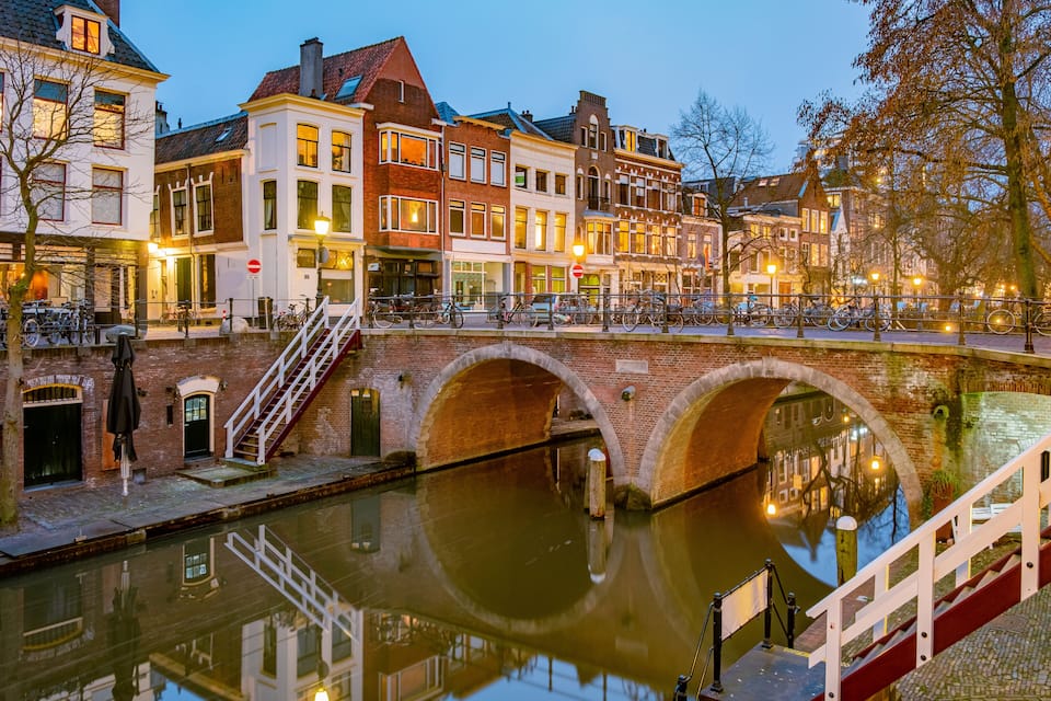 Un canal con un puente, edificios históricos y una hilera de bicicletas.
