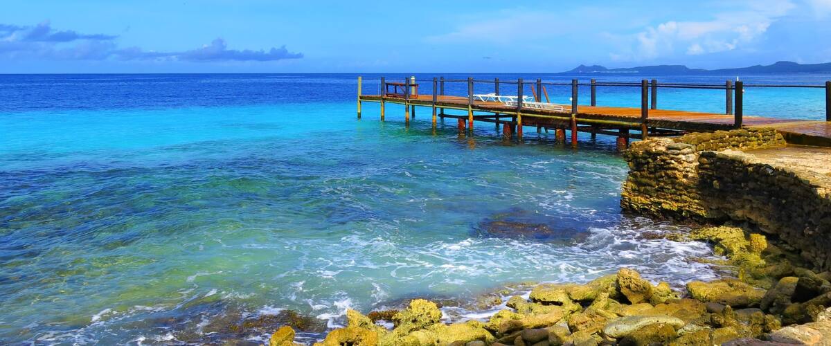 Wooden pier and tropical calm sea, sunny day. Azure ocean with jetty under the blue sky.