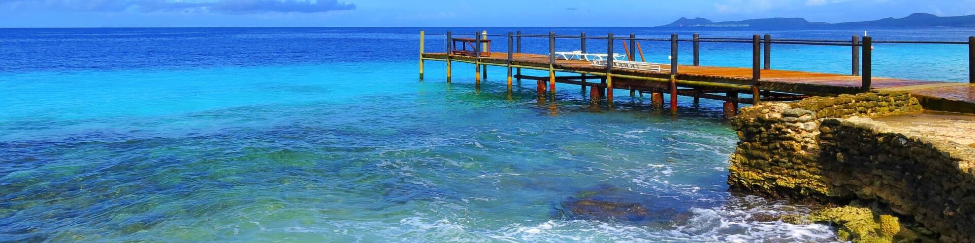 Wooden pier and tropical calm sea, sunny day. Azure ocean with jetty under the blue sky.