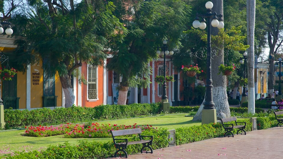 A park with benches, flower beds, and a building with barred windows.