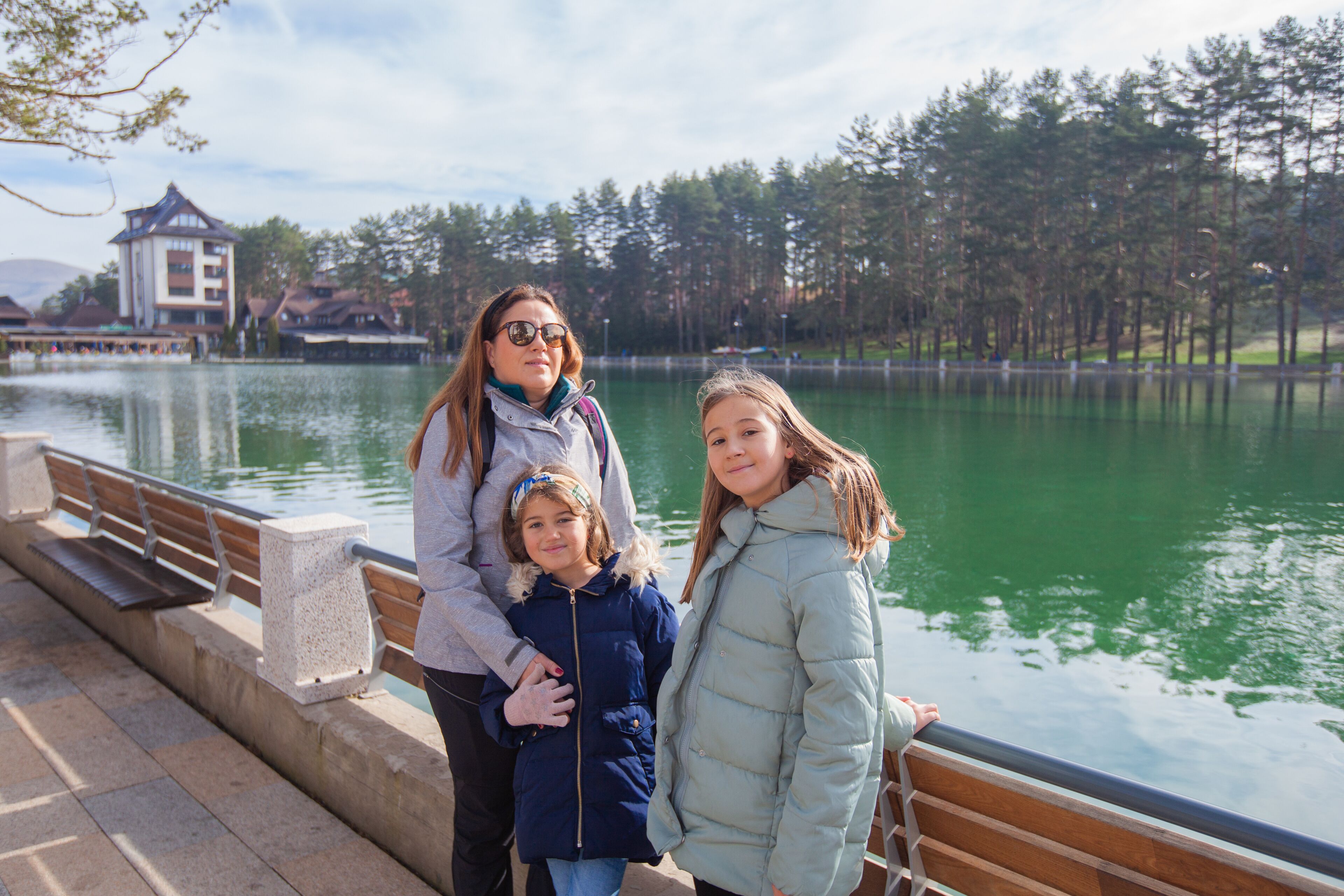 Family enjoy at lake in the touristic center surrounded pine forest in park, an autumn sunny day. Pleasant place for relaxing. Mountain Zlatibor, Serbia.	
