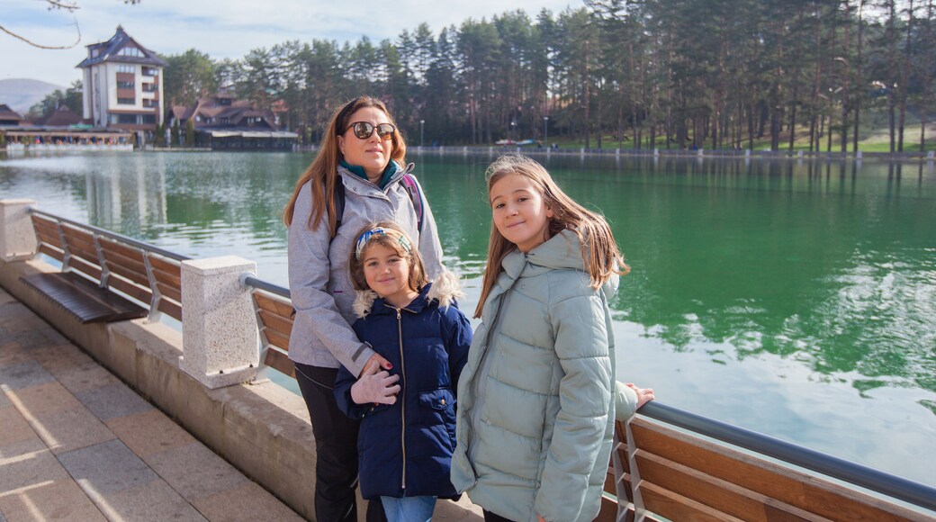 Family enjoy at lake in the touristic center surrounded pine forest in park, an autumn sunny day. Pleasant place for relaxing. Mountain Zlatibor, Serbia.