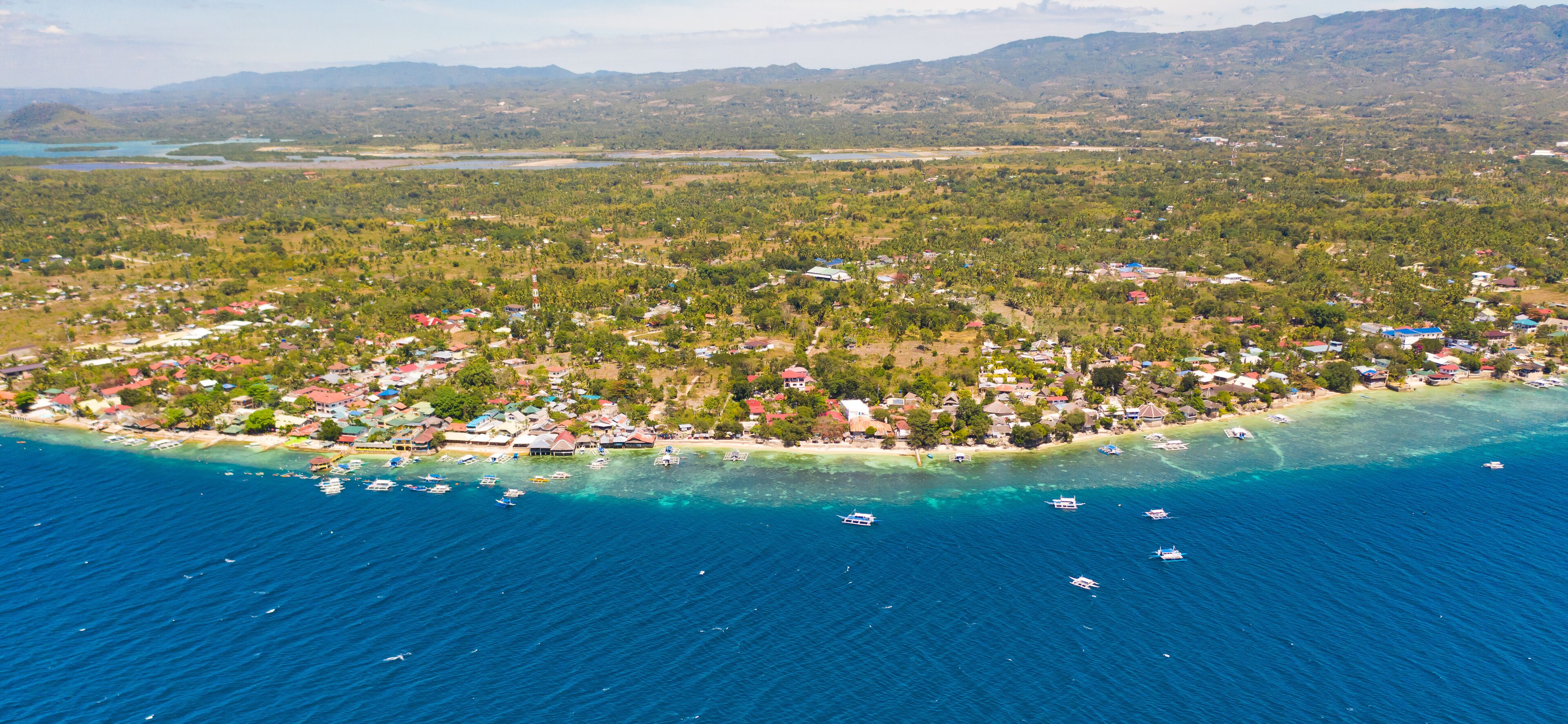 Coast of Cebu island, Moalboal, Philippines, top view. Philippine boats in a blue lagoon over coral reefs. Moalboal is a great place for diving and vacations.