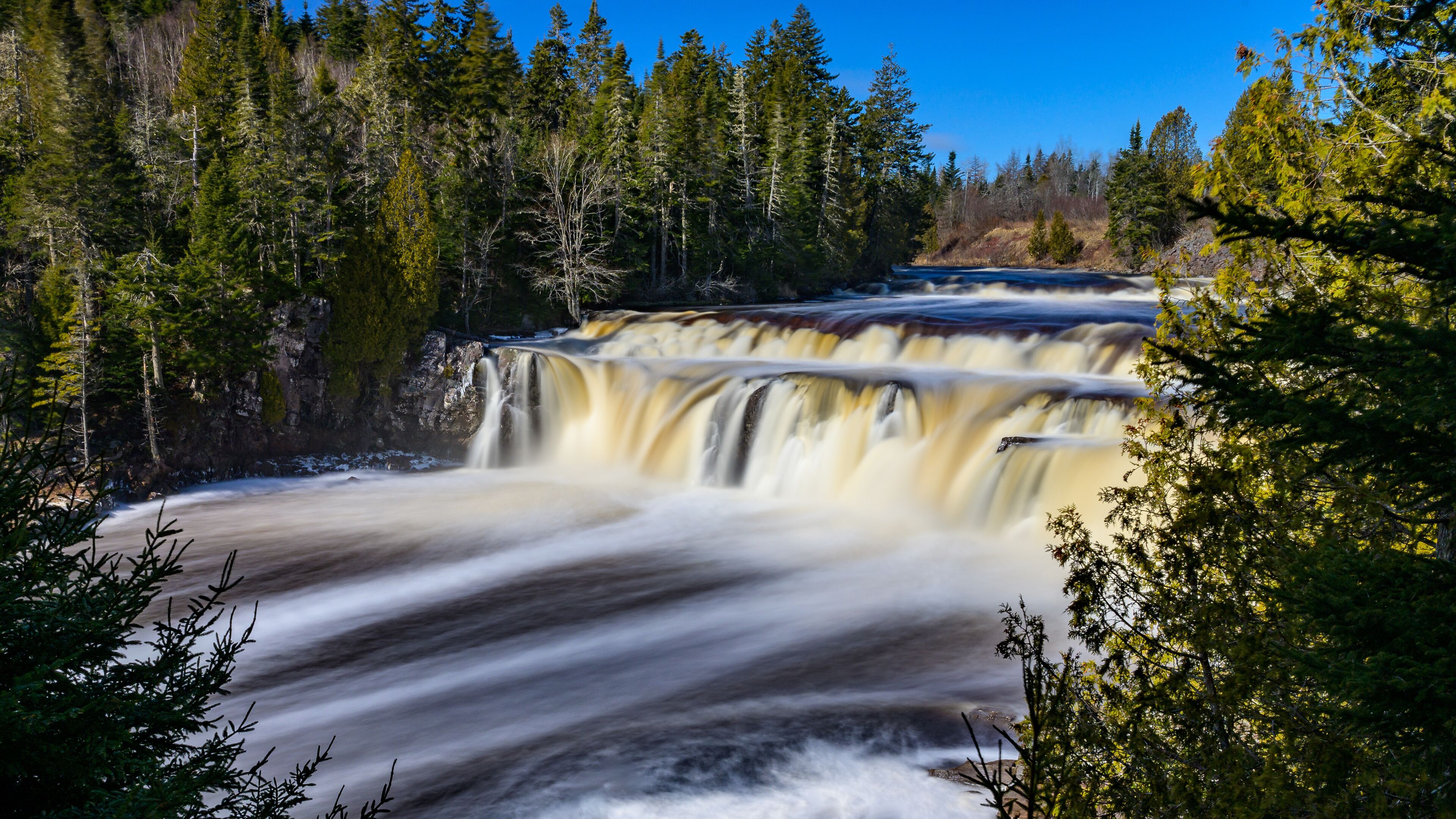 A waterfall cascading down a rocky cliff surrounded by dense forest.