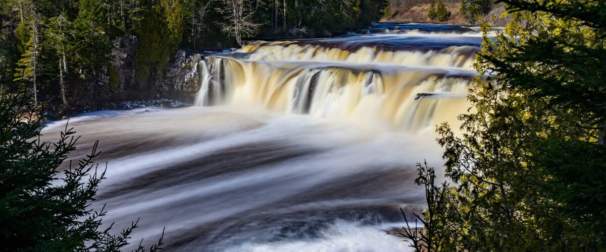 A waterfall cascading down a rocky cliff surrounded by dense forest.