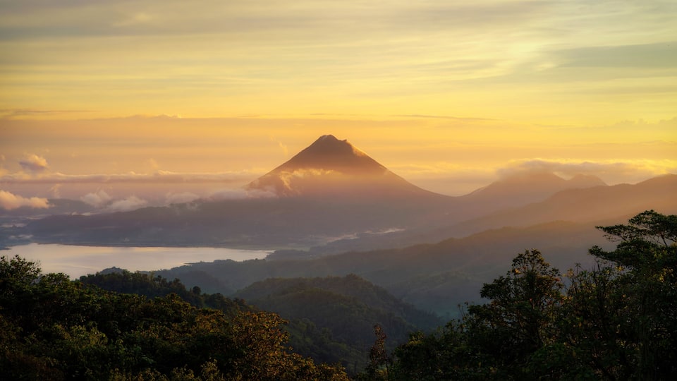 A mountain landscape with a prominent peak, surrounded by lush greenery and a valley below.