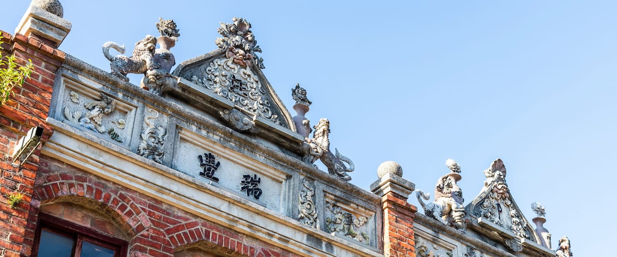A building with ornate stone carvings and statues, including lions and a dragon, and Chinese characters.