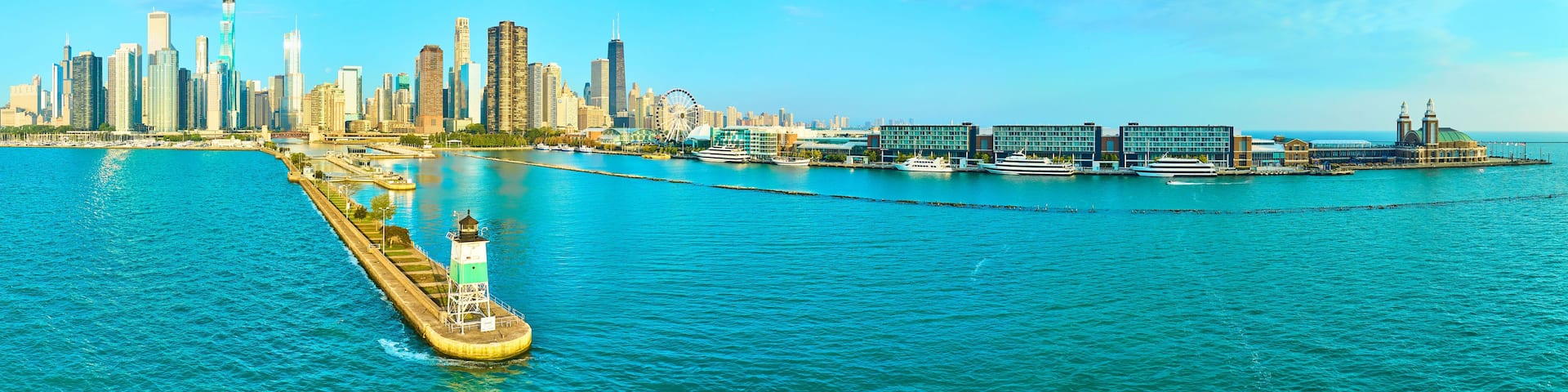 A coastal cityscape with a prominent skyscraper, a waterfront promenade, and a large Ferris wheel.