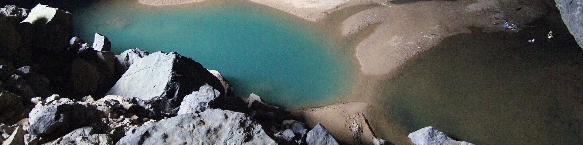 A cave with a sandy beach and turquoise water.