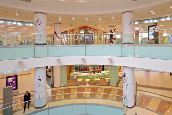 Et flerplans indkøbscenter med glasgelændere, store søjler og et centralt food court.