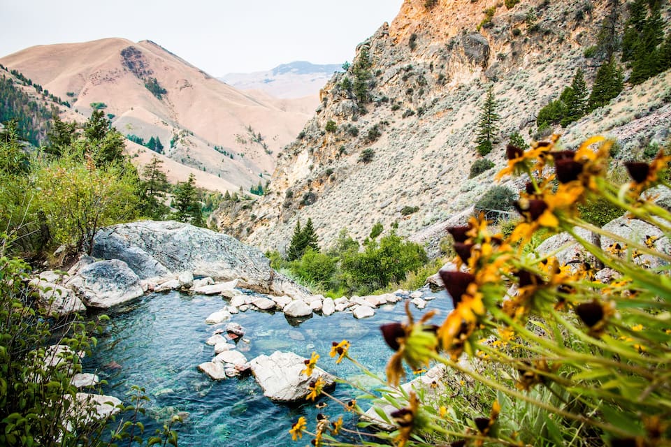 A clear mountain stream surrounded by rocky terrain and sparse vegetation.